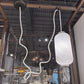 Ceiling light fixture with textured white shade and white cord in a modern interior setting.