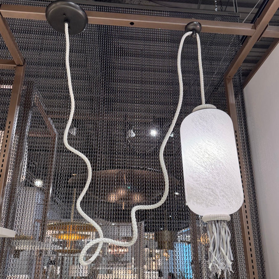 Ceiling light fixture with textured white shade and white cord in a modern interior setting.