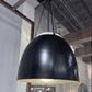 Black pendant light hanging in a modern interior setting with reflective walls.