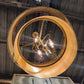 Gold circular light fixture with a reflective surface, showing a blurred reflection of a person.