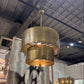 Gold pendant light fixture hanging in a showroom with other lighting options.