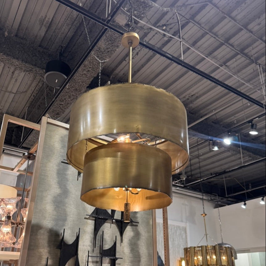 Gold pendant light fixture hanging in a showroom with other lighting options.