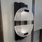 Decorative wall sconce with black and glass design on a white wall.