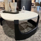 Modern coffee table with marble top and black base in a showroom setting