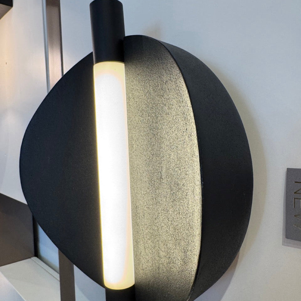 Modern wall-mounted light fixture with black and gray design on a white wall.