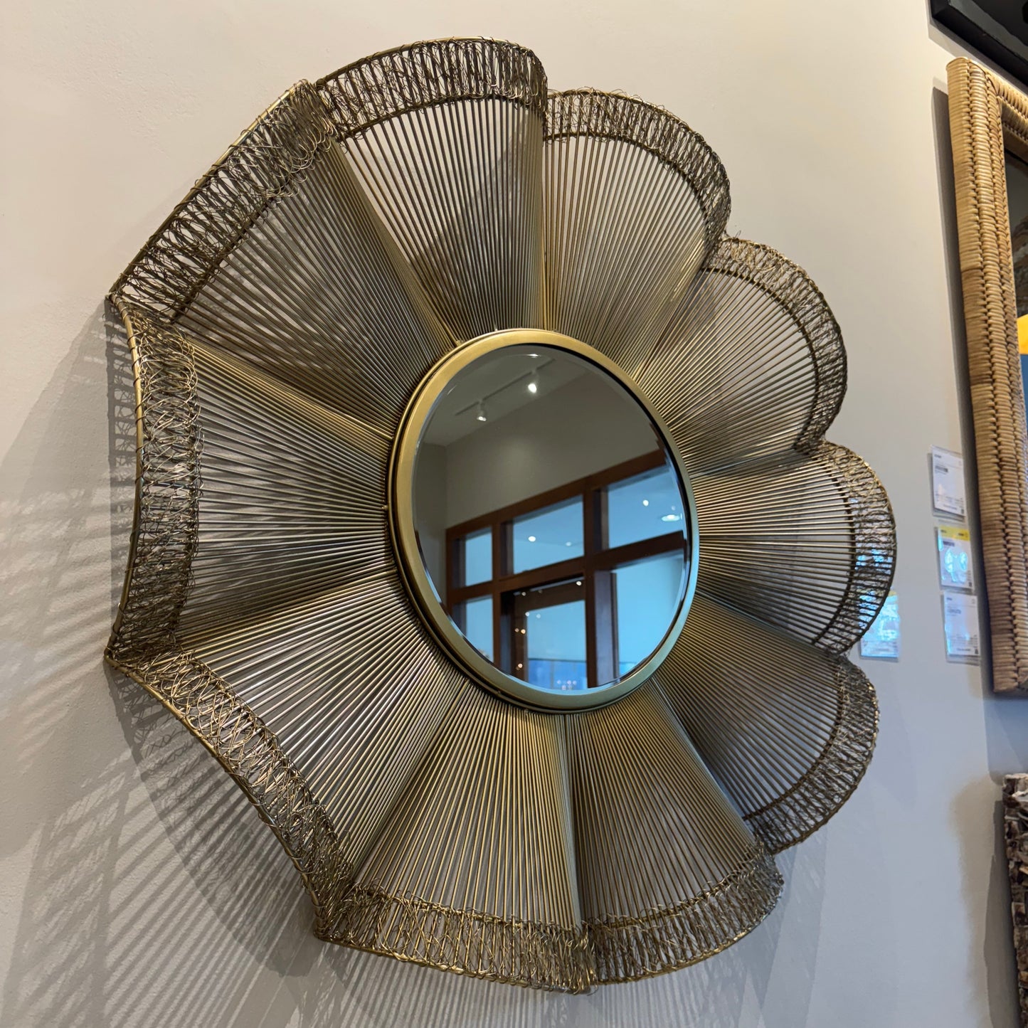 Decorative wall mirror with a sunburst design on a white surface
