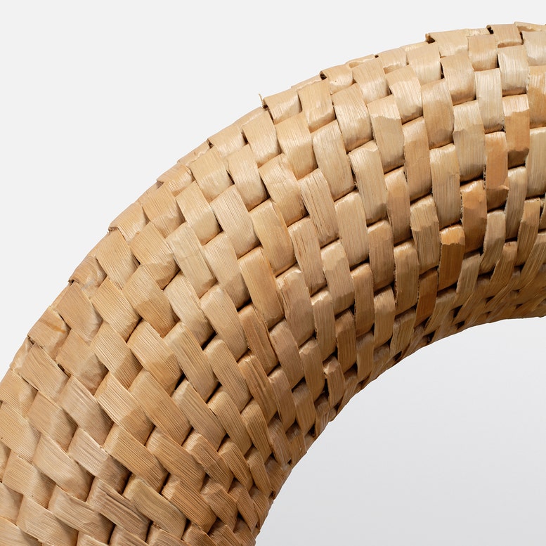 Close-up of a woven wooden ring on a light gray background