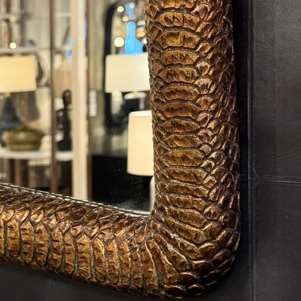 Decorative mirror with textured bronze frame in a room setting