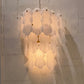 Wall-mounted light fixture with shell-like design on a textured wall.