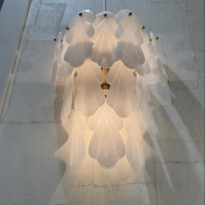 Decorative wall light fixture casting a soft glow on a marble wall.