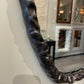 Decorative mirror with a textured black frame on a wall.