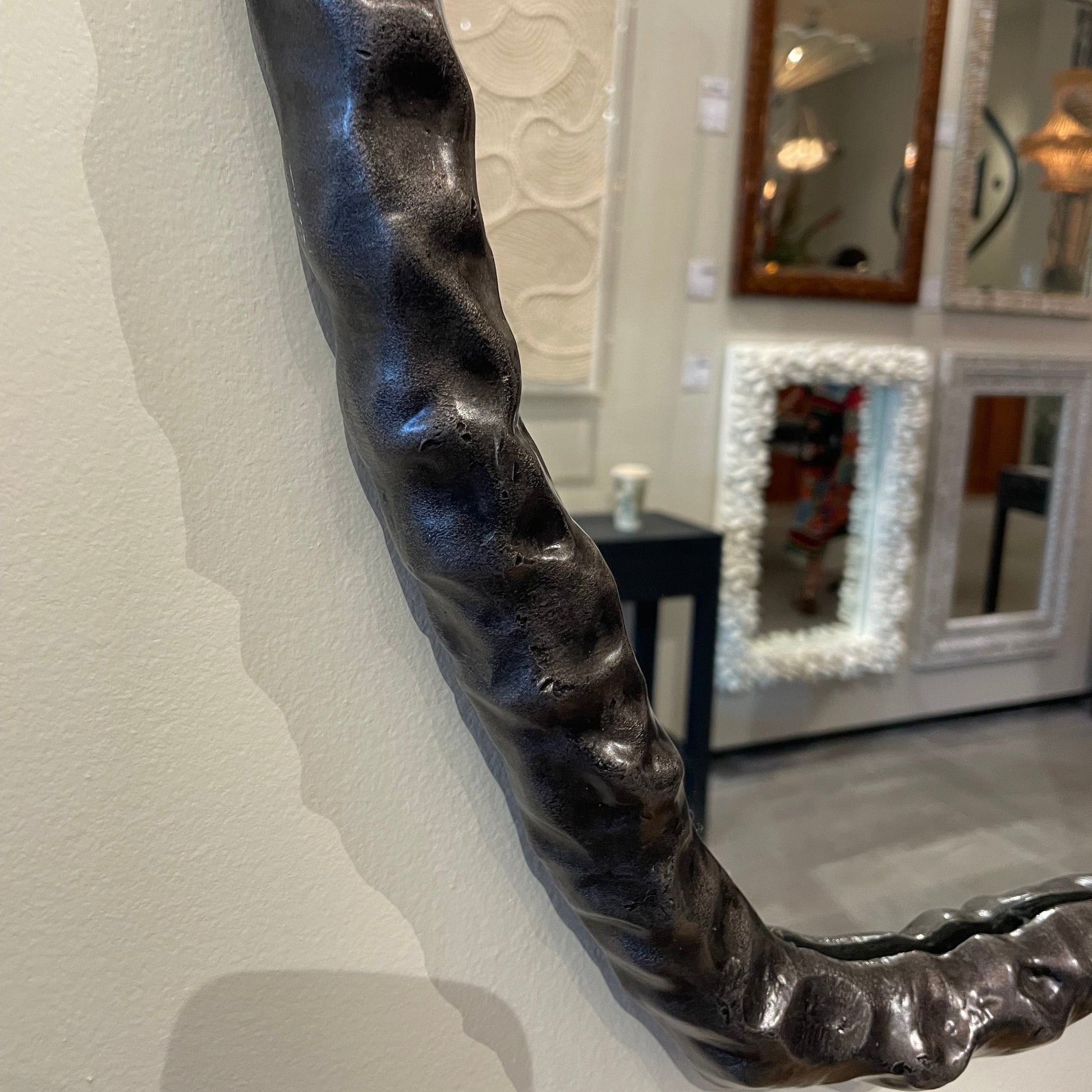 Decorative mirror with a textured black frame on a wall.