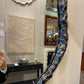 Decorative mirror with textured silver frame in a room with wall art and furniture.