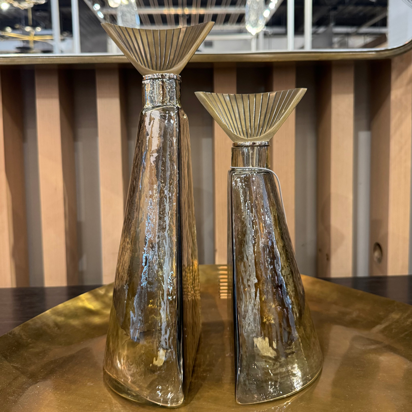 Two glass vases on a reflective surface with a blurred indoor background