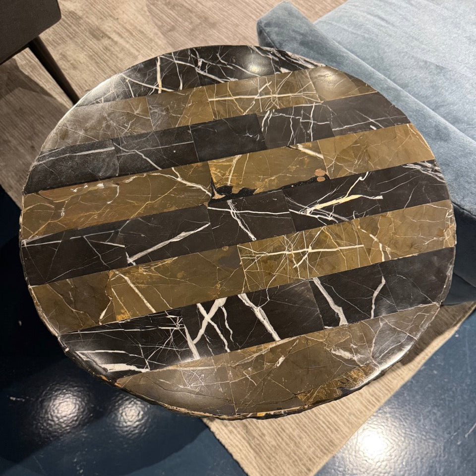 Round marble coaster with black and gold pattern on a wooden surface