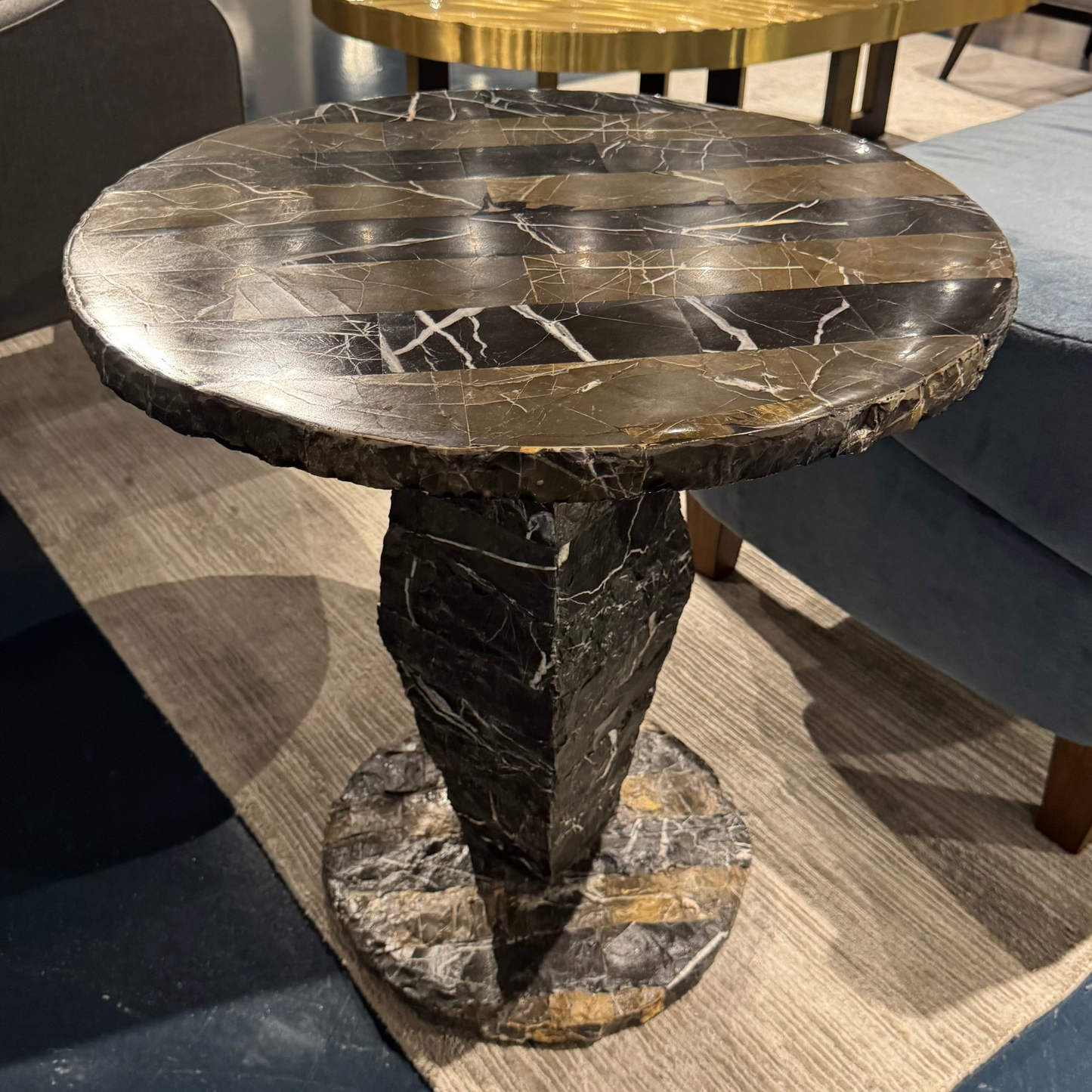 Round marble table in a showroom setting with furniture around