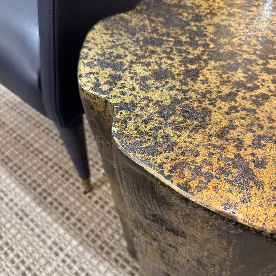 Close-up of a textured round table with a chair partially visible.