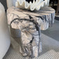 Marble-patterned side table with decorative item on a patterned floor.