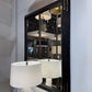 Decorative mirror with black frame on a wall with a lamp reflection