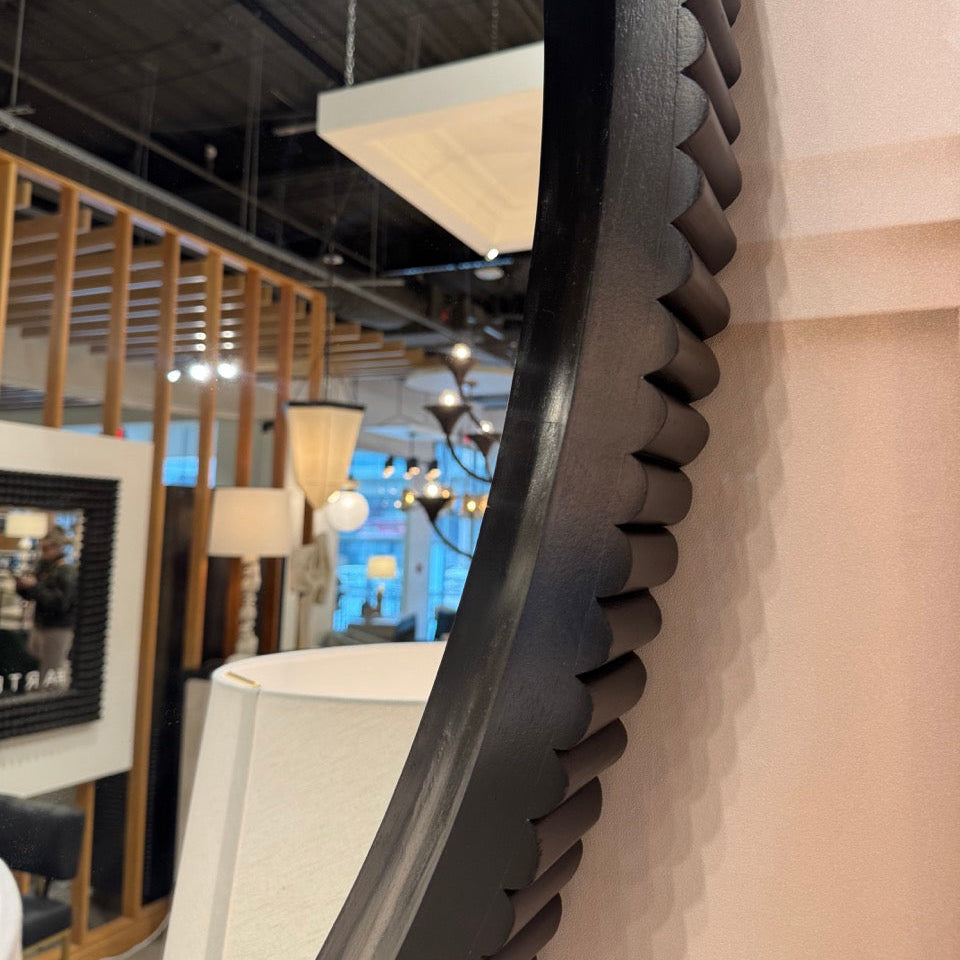 Large decorative mirror with a unique frame design on a wall.