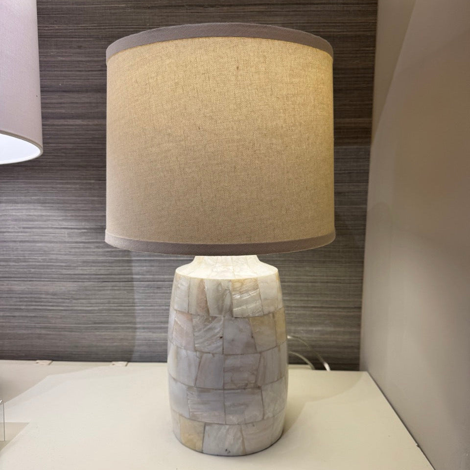 Table lamp with a textured base and beige shade on a surface.