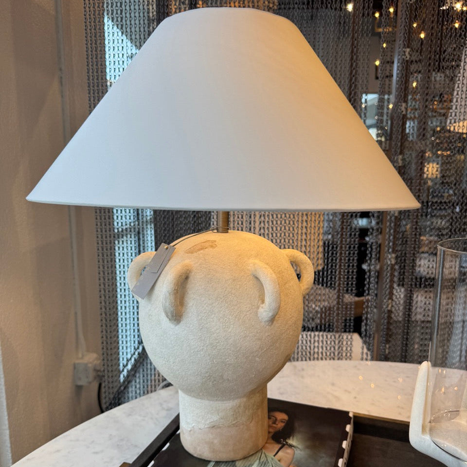 Lamp with a decorative head on a table next to a magazine