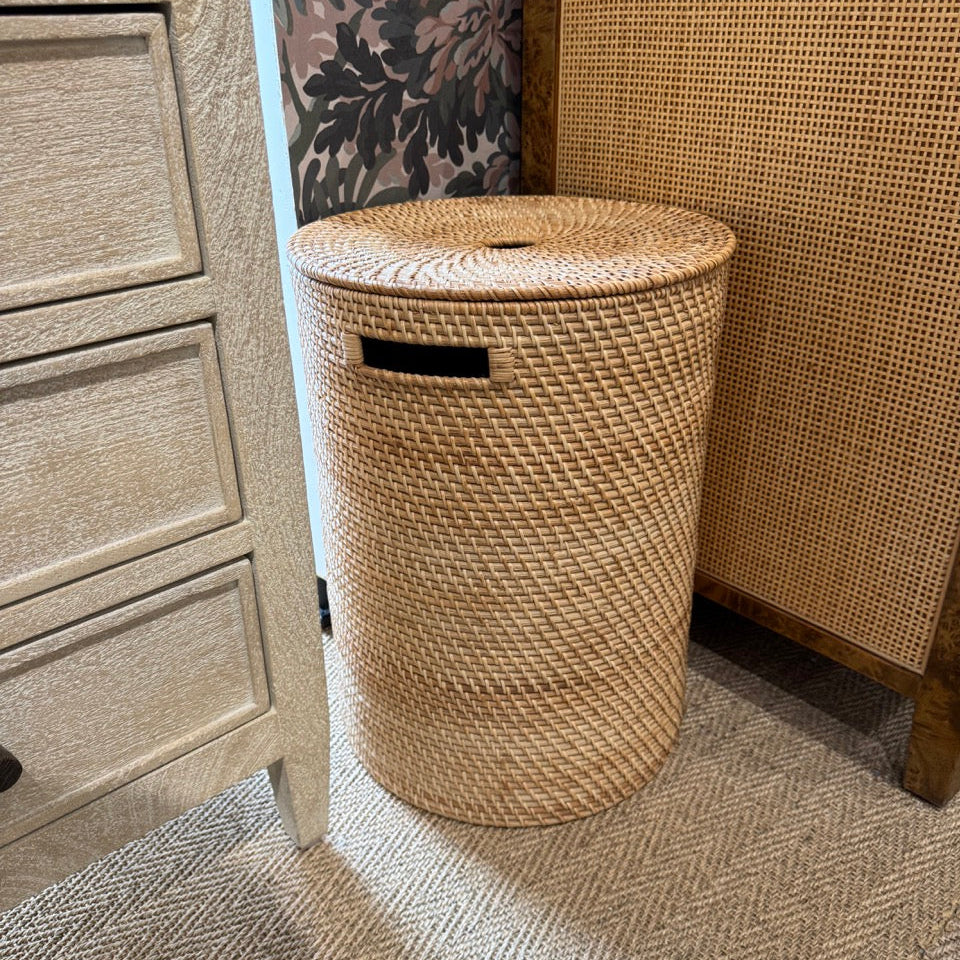 Woven laundry basket in a room with textured walls and carpet.