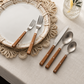 Five-piece flatware set with polished silver metal heads and warm brown wooden handles