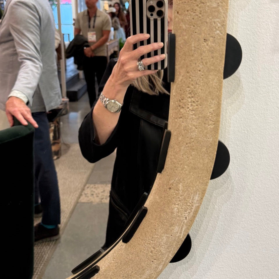 Person taking a mirror selfie with a decorative mirror in a store setting