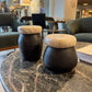 Two wooden stools with stone tops on a marble table in a modern interior setting.