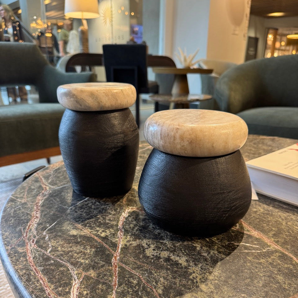 Two wooden stools with stone tops on a marble table in a modern interior setting.
