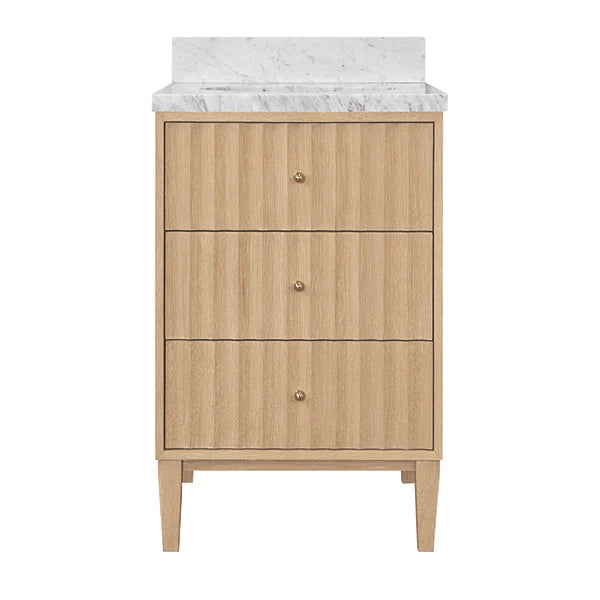 A three-drawer bathroom vanity cabinet in a light natural wood finish with small round metallic knobs, topped with a white marble countertop and backsplash, shown on a plain white background.