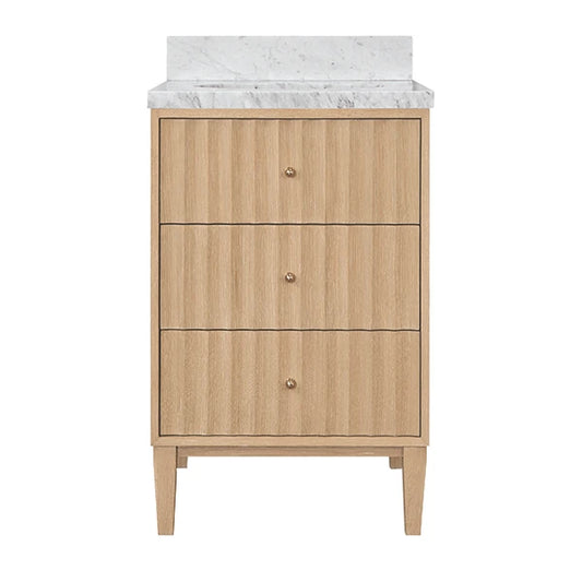 A three-drawer bathroom vanity cabinet in a light natural wood finish with small round metallic knobs, topped with a white marble countertop and backsplash, shown on a plain white background.