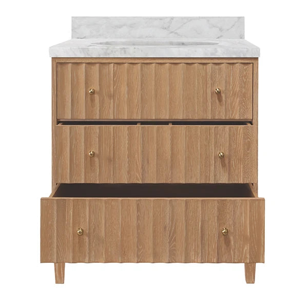 A three-drawer wooden vanity cabinet with a white marble countertop and backsplash, featuring small brass knobs and tapered legs, shown against a plain white background.