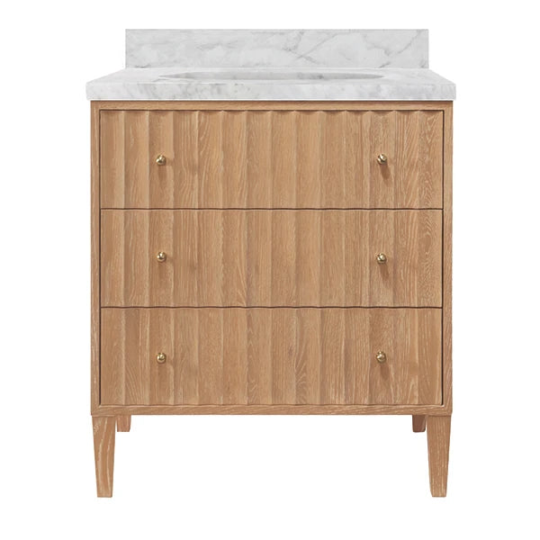 A three-drawer wooden vanity cabinet with a white marble countertop and backsplash, featuring small brass knobs and tapered legs, shown against a plain white background.