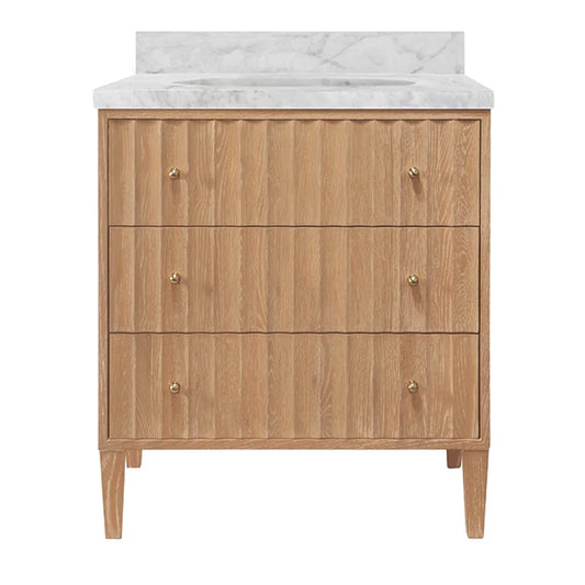 A three-drawer wooden vanity cabinet with a white marble countertop and backsplash, featuring small brass knobs and tapered legs, shown against a plain white background.