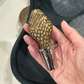 Hand holding a decorative bottle stopper with intricate design against a neutral background