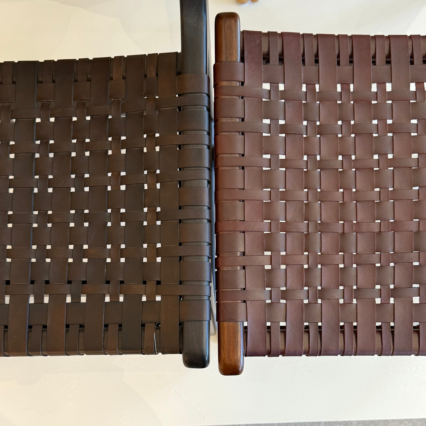 Brown woven chair with a person wearing black shoes standing on a wooden floor.