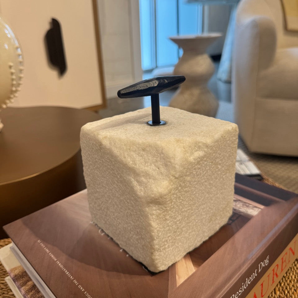 Decorative cube with a black handle on top of a book in an indoor setting