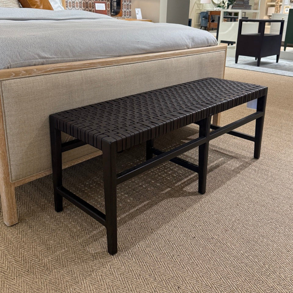 Bedroom setting with a bed and black woven bench.
