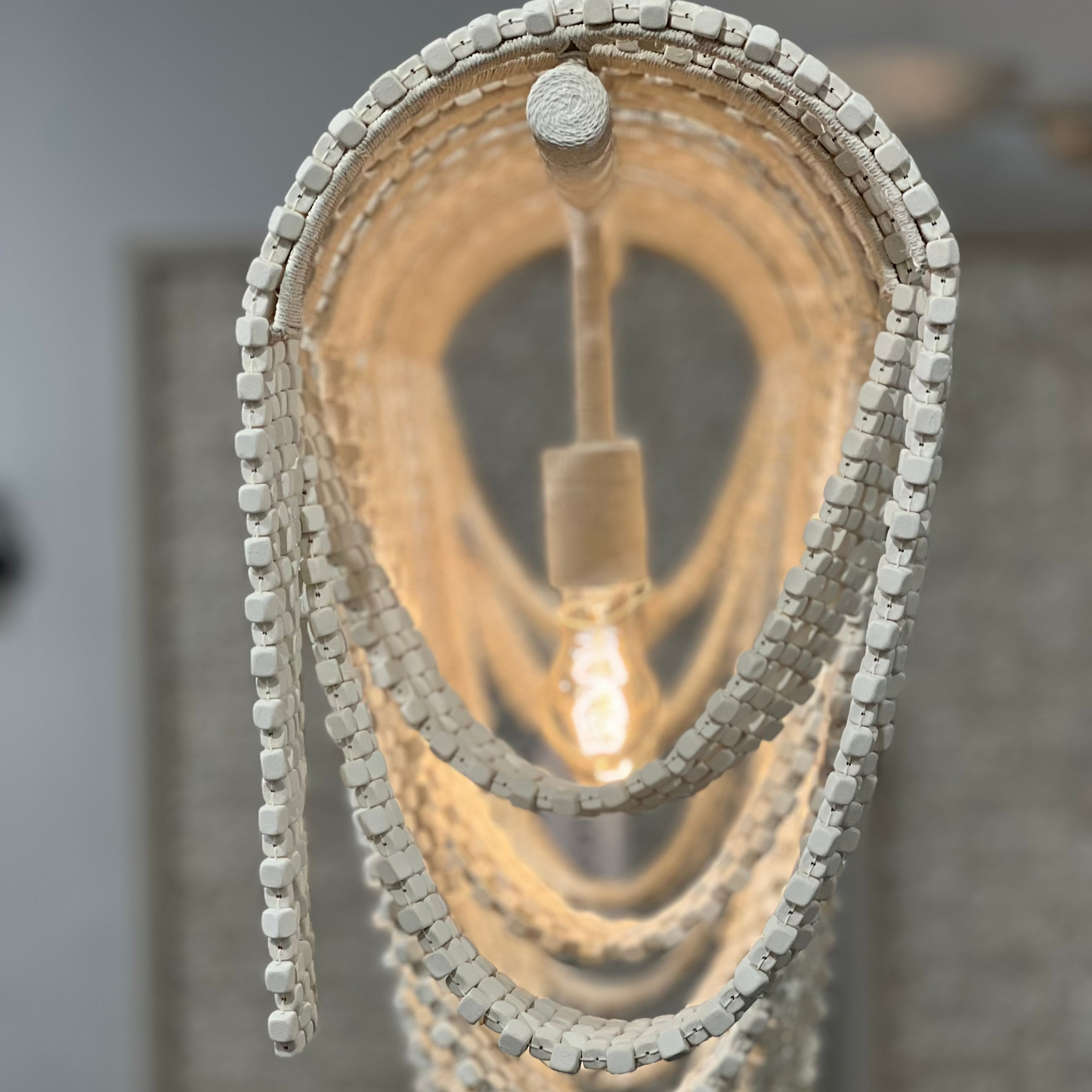 Close-up of a decorative pendant light with textured chain design against a neutral background