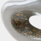 Close-up of a glossy ceramic vessel with a smooth off-white exterior and a dark gray interior patterned with brown and gold speckled spots.