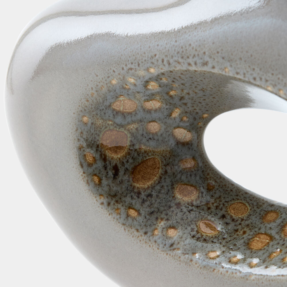 Close-up of a glossy ceramic vessel with a smooth off-white exterior and a dark gray interior patterned with brown and gold speckled spots.