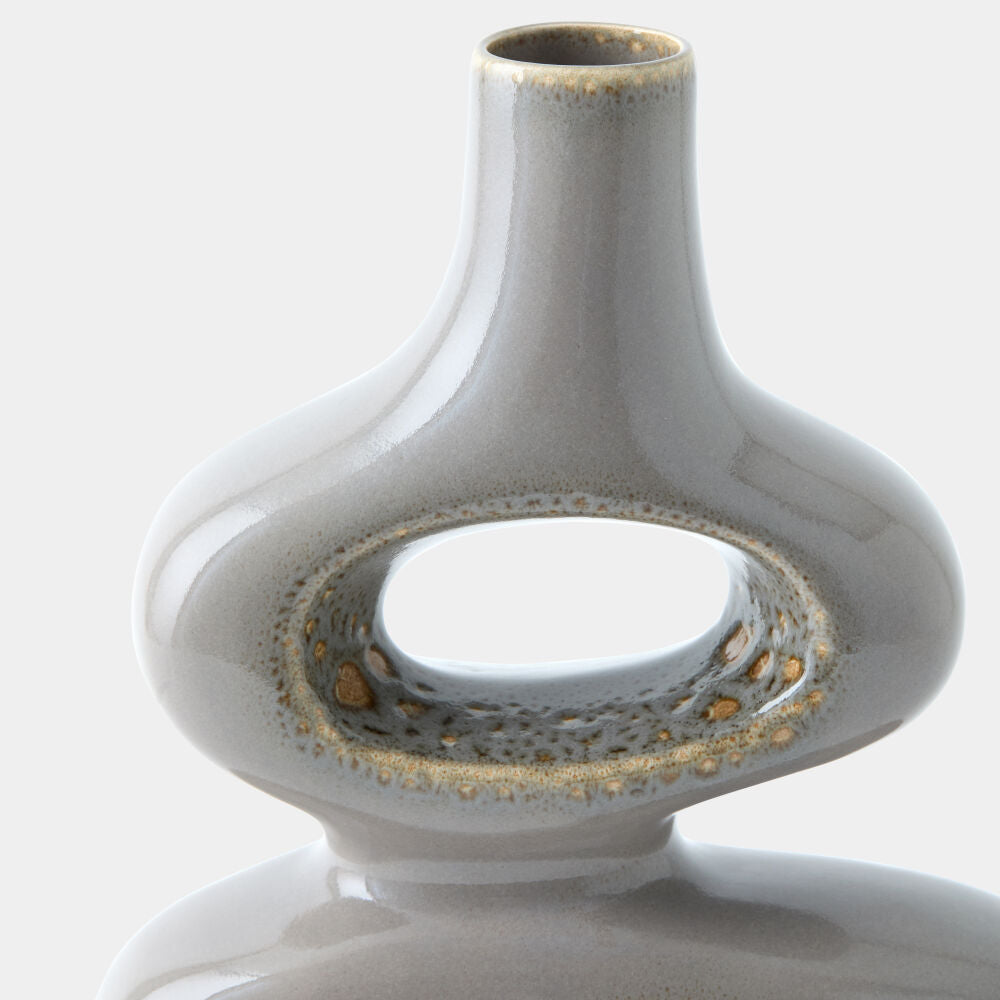 Close-up of a ceramic vase with a glossy light gray glaze and small gold speckled accents around the ring handle, shown against a plain light background.