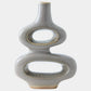 A modern, sculptural ceramic vase with a glossy light gray finish and textured metallic gold accents around the two central loops and base, set against a plain light gray background.