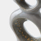 Close-up of a glossy ceramic sculptural vase with organic looped forms and speckled gold-brown oxidized details on a white background.
