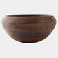 A large, round wooden bowl with a rich dark brown finish and visible natural wood grain patterns, set against a plain light gray background.