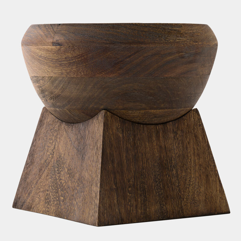 A dark brown wooden bowl with a sculptural, tiered geometric base, shown against a plain light gray background.