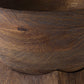 Close-up of a dark brown wooden bowl showing the rich wood grain texture and curved interior edge.