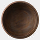 A top-down view of a dark brown wooden bowl with visible wood grain, set against a plain light gray background.